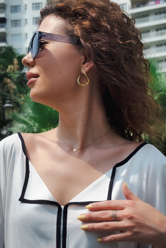 Woman wearing sunglasses and a white top with black trim outdoors